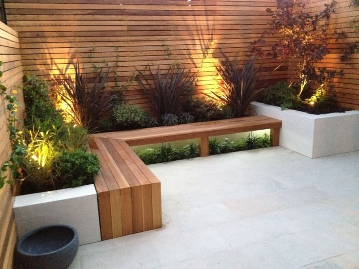 a wooden bench sitting in the middle of a garden next to a tall planter