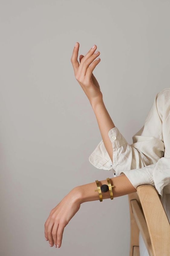 a woman sitting in a chair holding her hand up to the side with both hands