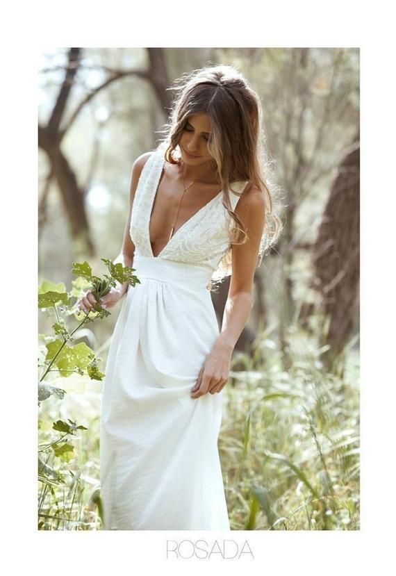 a beautiful woman in a white dress standing in the woods with her hands on her hips