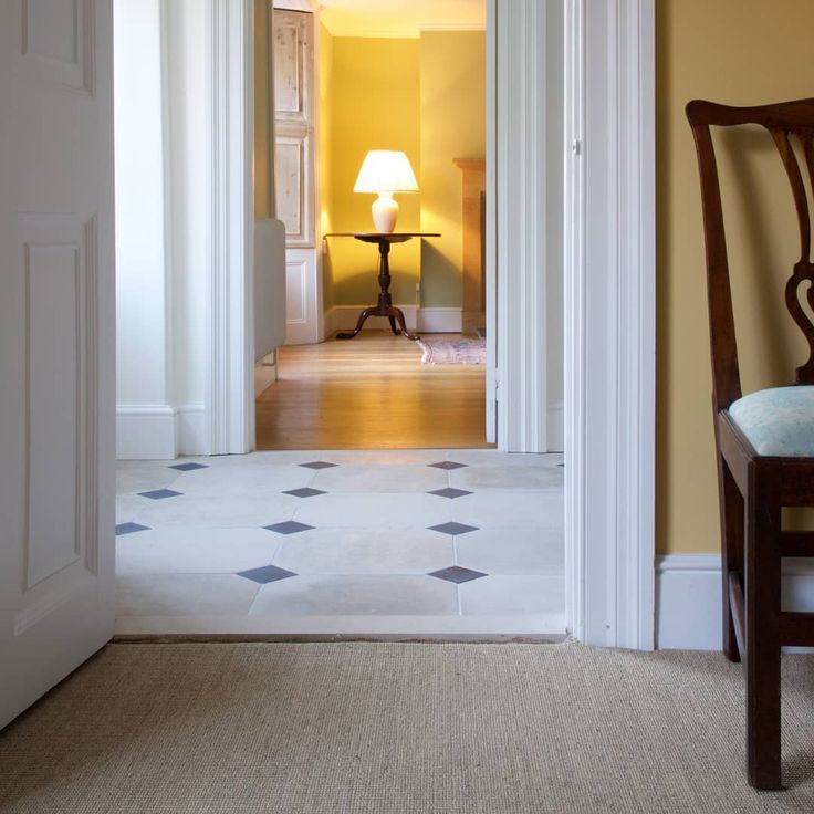 an open door leading to a room with a lamp on the table and chairs in it