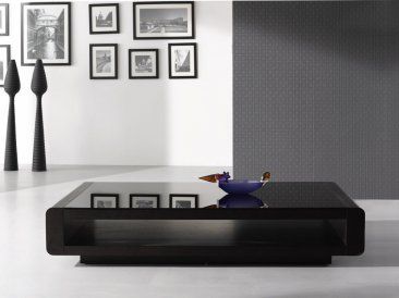 a black coffee table sitting on top of a white floor next to pictures and lamps