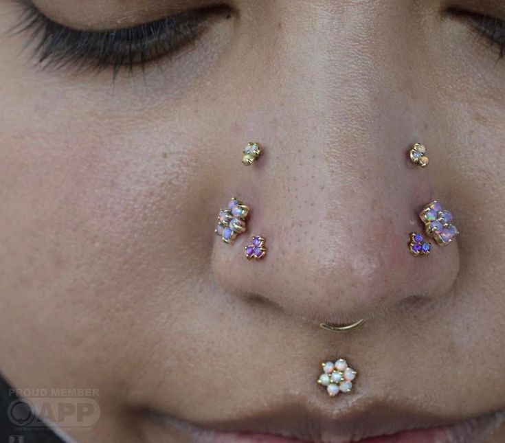 a close up of a person with piercings on her nose and nose ring in the shape of flowers