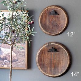 two wooden plates with birds on them are next to an olive tree in front of a framed photo