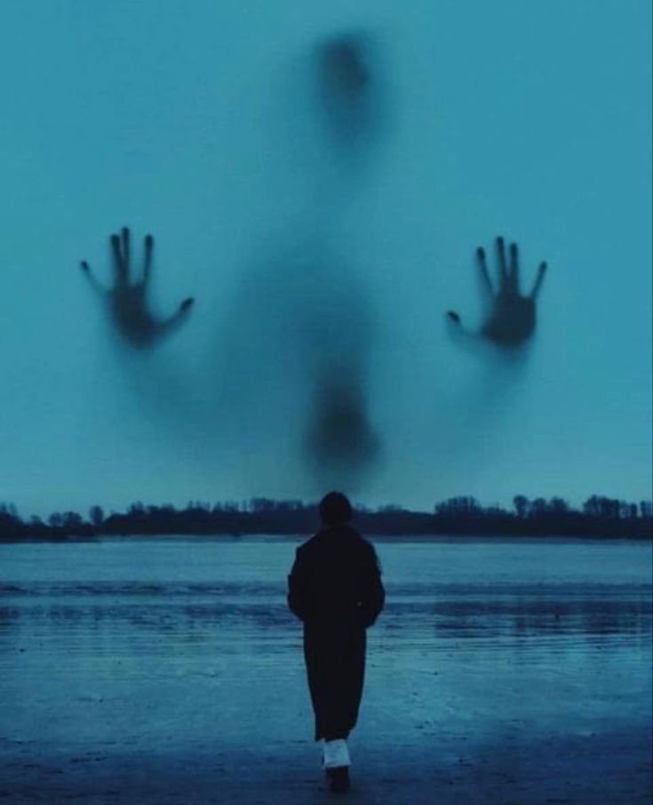 a person standing in front of a body of water with their hands up to the sky