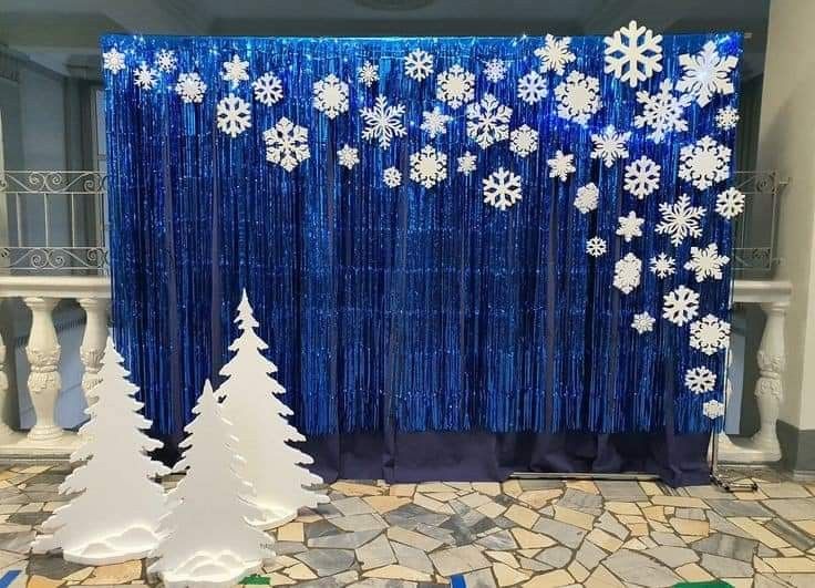 snowflakes and trees are on display in front of a blue curtain with sequins