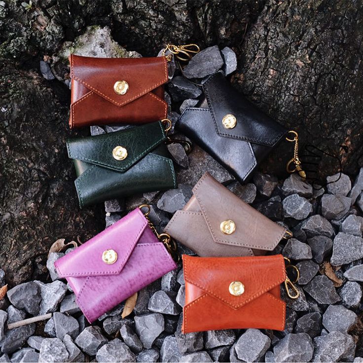 four different colored leather purses sitting on rocks