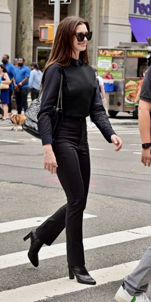 a woman in black is crossing the street