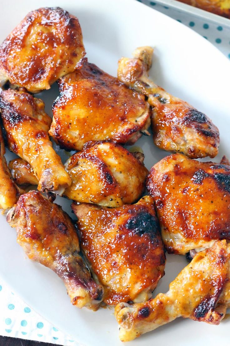 chicken wings on a white plate next to a casserole dish with blue dots