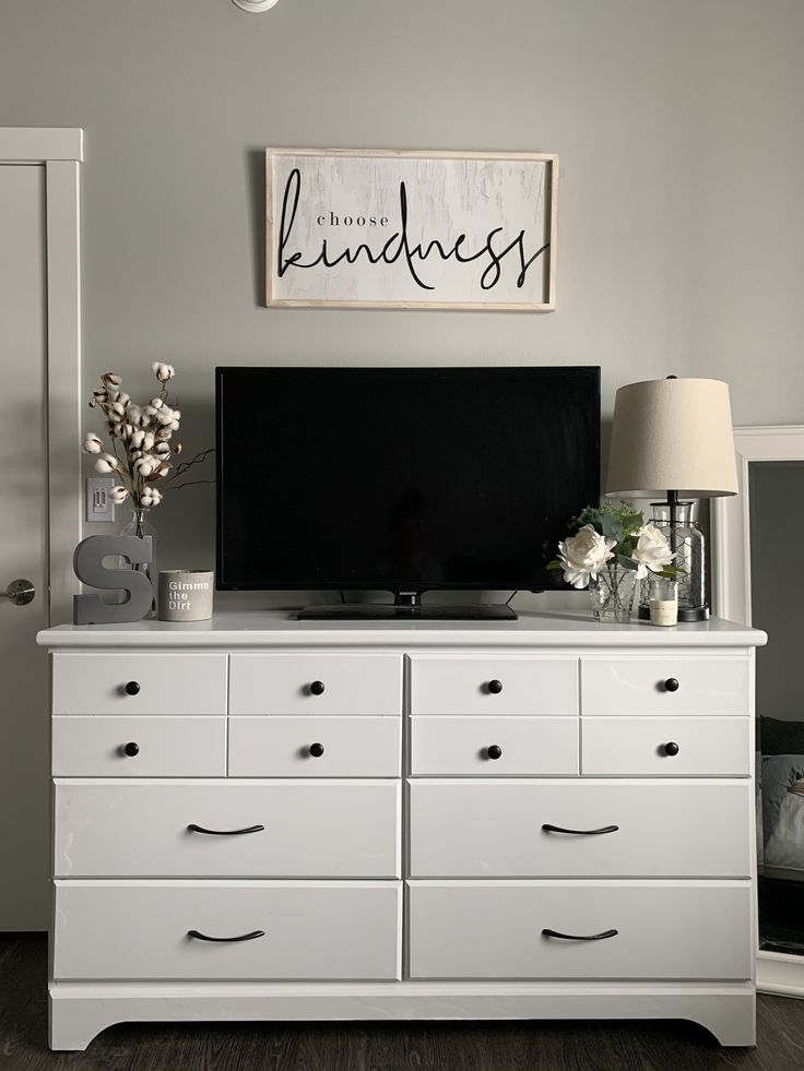 a white dresser with drawers and a television on top