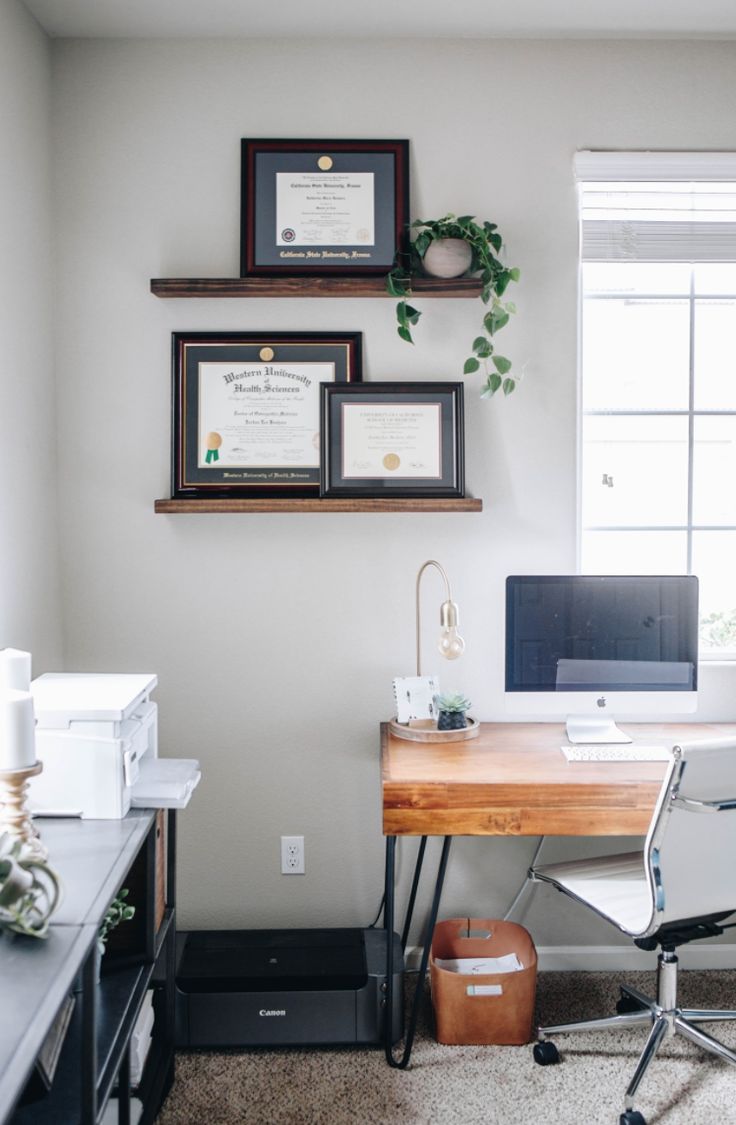 a home office with two framed pictures on the wall and a computer desk in front of it