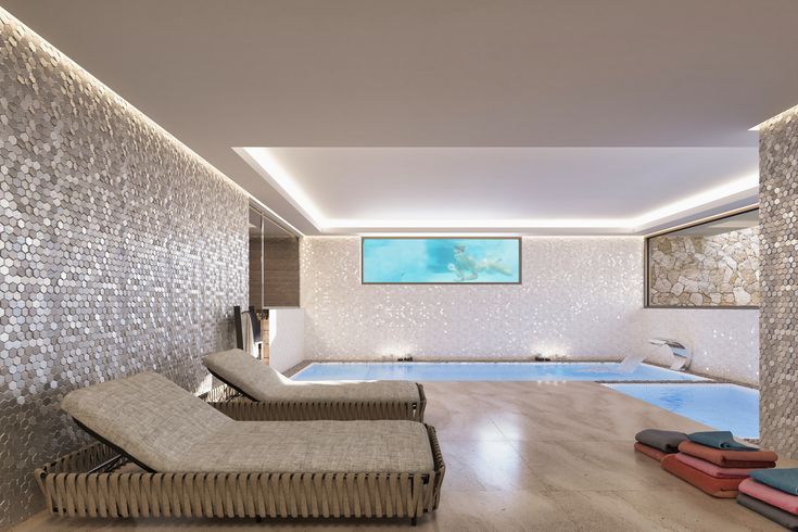 an indoor swimming pool with chaise lounges next to it and a television on the wall