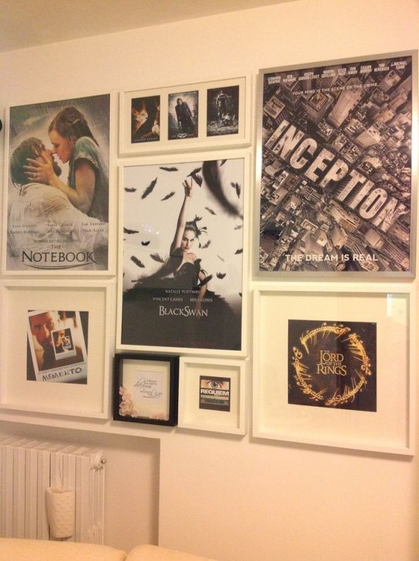 a wall with many different movie posters and pictures on it, along with a couch