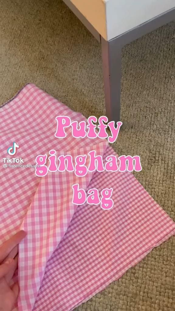 a pink gingham bag sitting on top of a floor next to a table