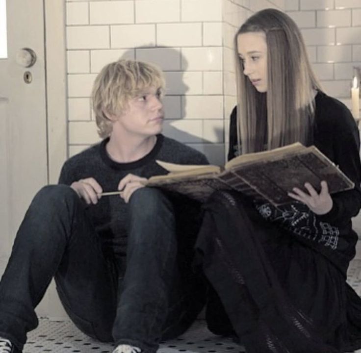 two people sitting on the floor reading a book