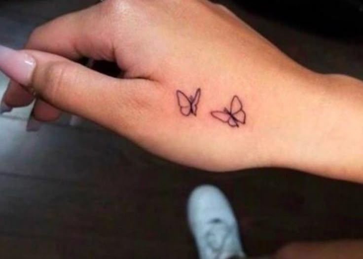 a small tattoo on the left wrist is shown in black ink, and has two butterflies