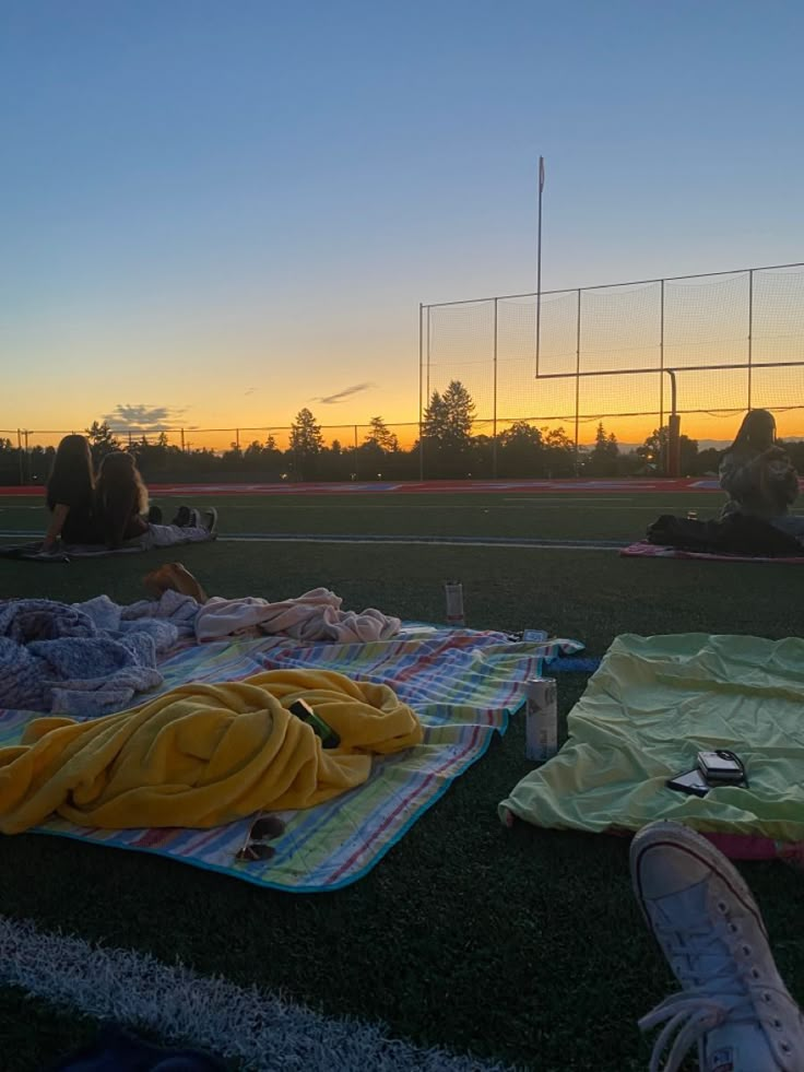 some people are laying on the grass and having a good time at sun set with their feet in the air