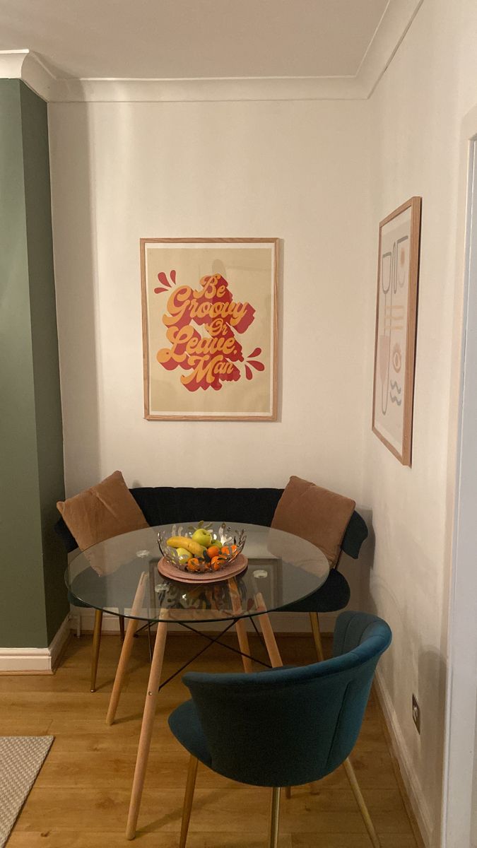 a glass table with two chairs and a bowl of fruit on it in a small room