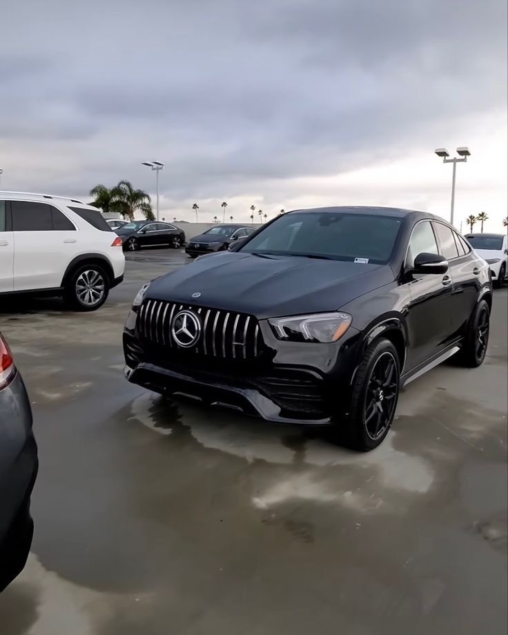 a mercedes benz suv is parked in a parking lot with other cars and trucks behind it