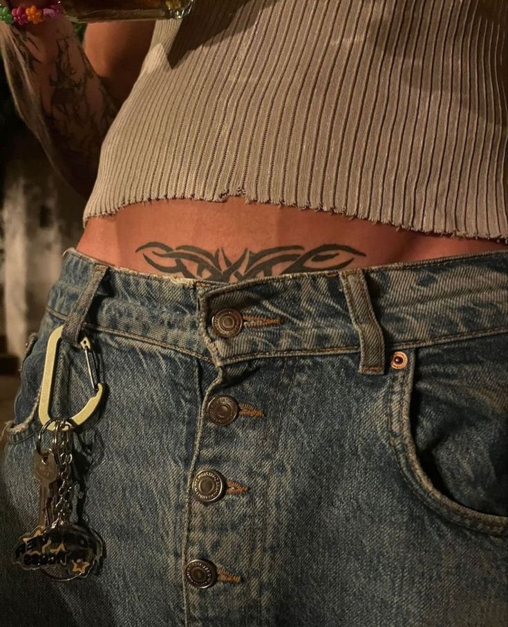 a person with tattoos on their stomach wearing jeans