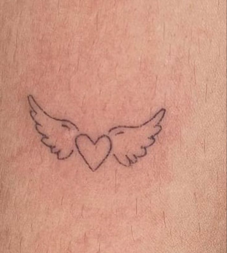 a small heart with wings tattoo on the side of someone's leg and chest