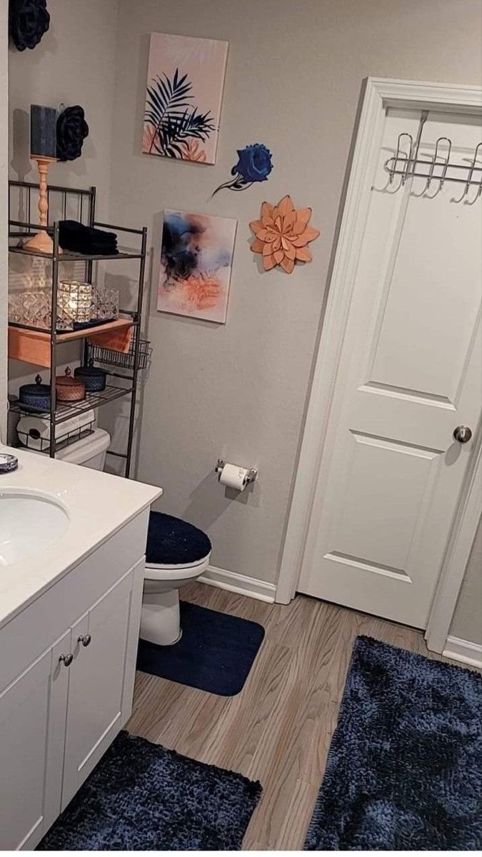 a white bathroom with blue rugs and pictures on the wall