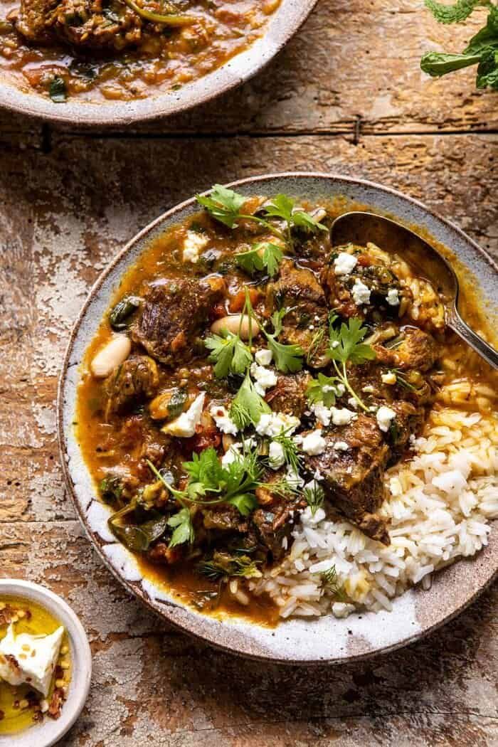 two bowls filled with stew and rice on top of a wooden table