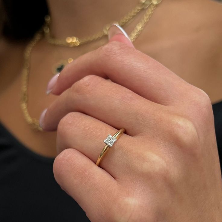 a close up of a person wearing a ring with a diamond on the middle finger