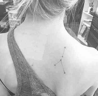 the back of a woman's neck with a small star tattoo on her left shoulder