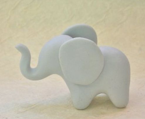 an elephant figurine sitting on top of a white surface