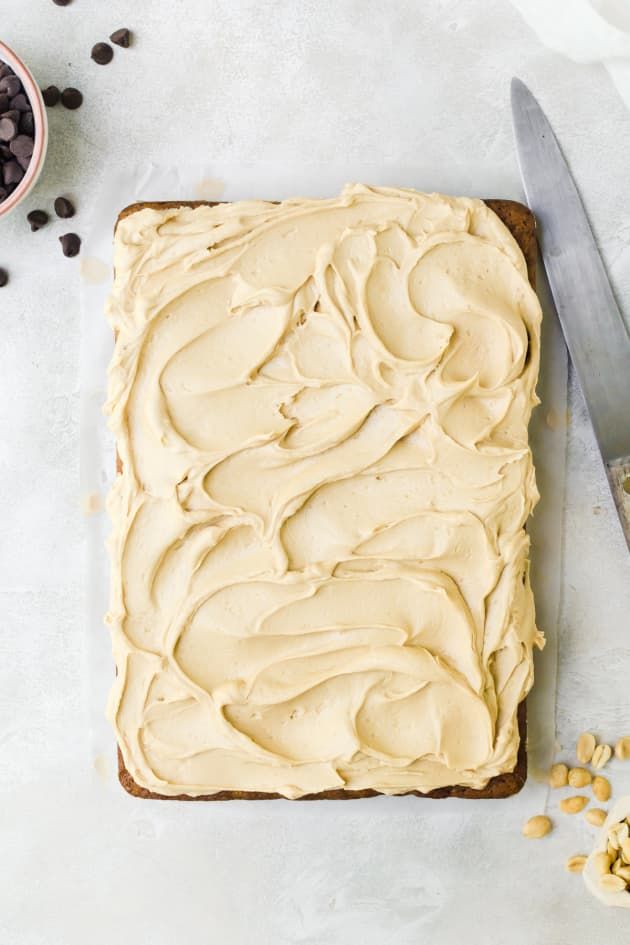 a frosted cake sitting on top of a table next to a knife and bowl