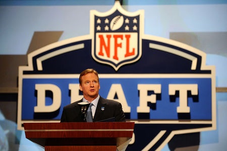 a man standing at a podium in front of a nfl logo