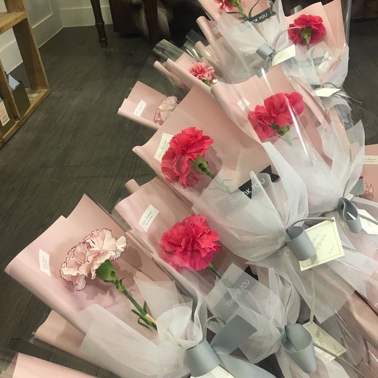 a bunch of pink flowers sitting on top of white paper wrapped in cellophane