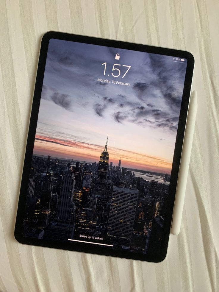 an ipad on top of a bed with the new york skyline in the back ground