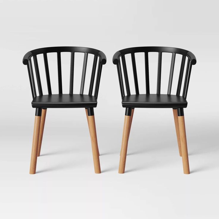 two black chairs with wooden legs are shown side by side in front of a white background