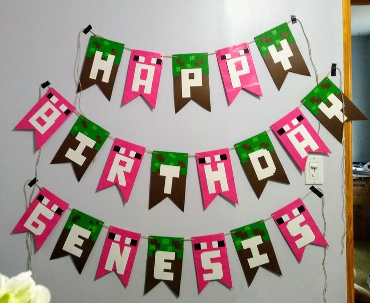 a happy birthday banner with pink, green and brown paper streamers hanging from the wall