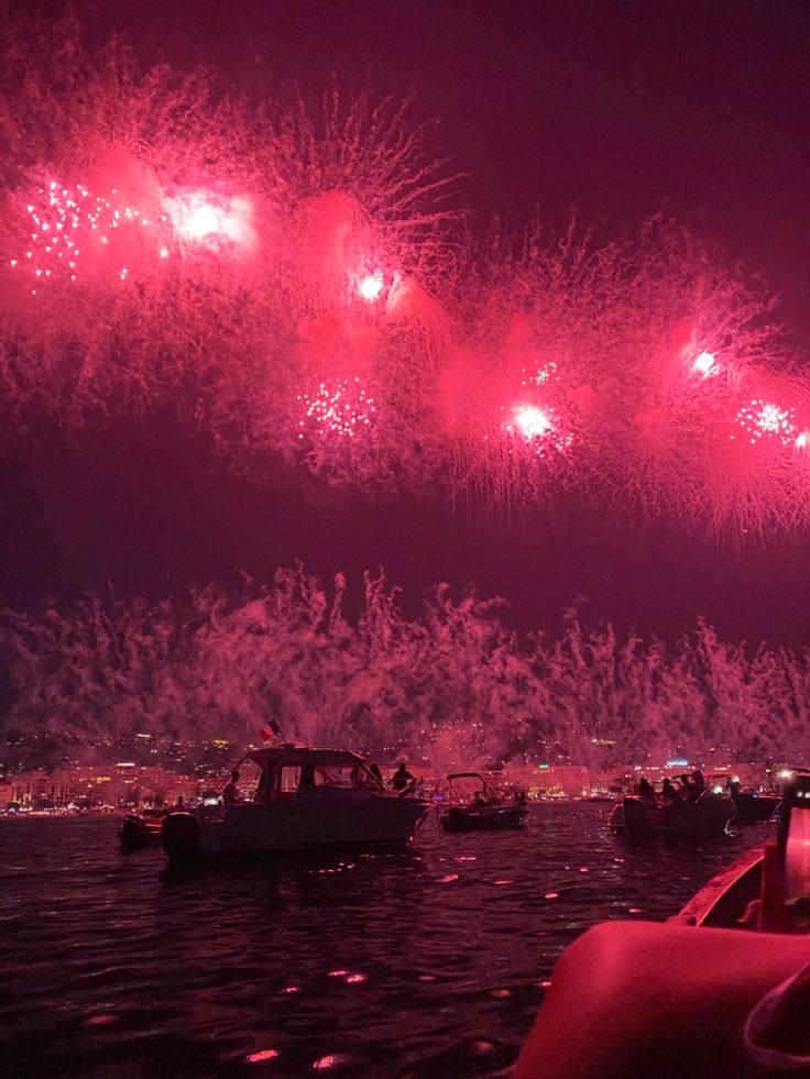 fireworks are lit up over boats in the water