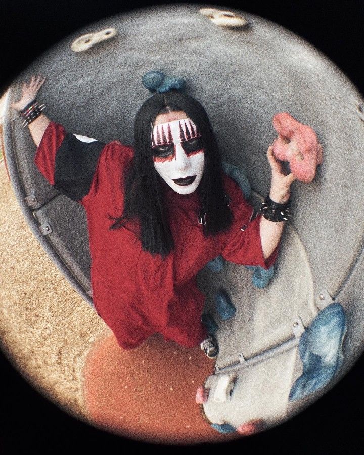 a woman with black makeup and white face paint holding a doughnut