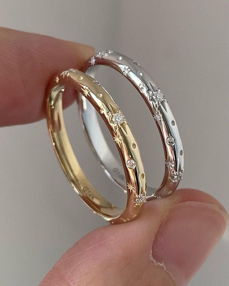 two gold wedding rings with diamonds on each one being held in someone's hand