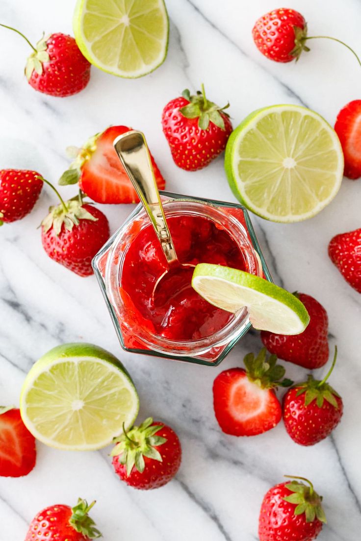 strawberries and limes surrounding a jar of strawberry margarita