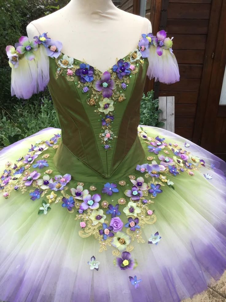 a green and purple tutu with flowers on it's chest, sitting on a mannequin