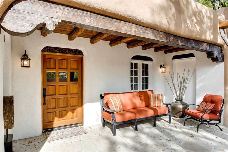 an orange couch sitting on top of a patio next to a wooden door and window