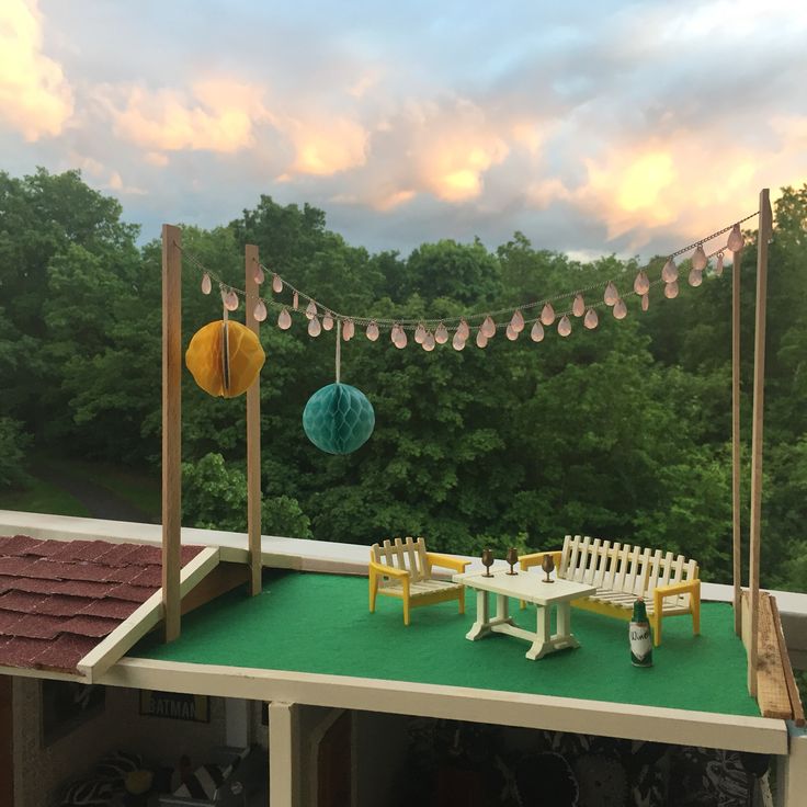 a table and chairs on top of a roof with string lights hanging from the ceiling