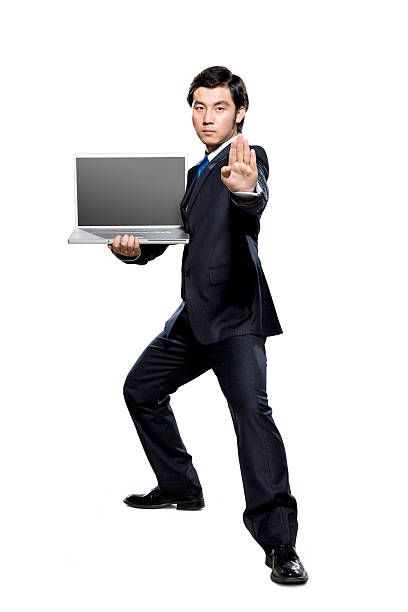 a man in a suit is holding a laptop and pointing to the side with his finger