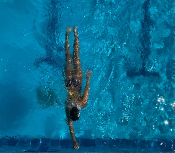 an overhead view of a man swimming in a pool with his back to the camera