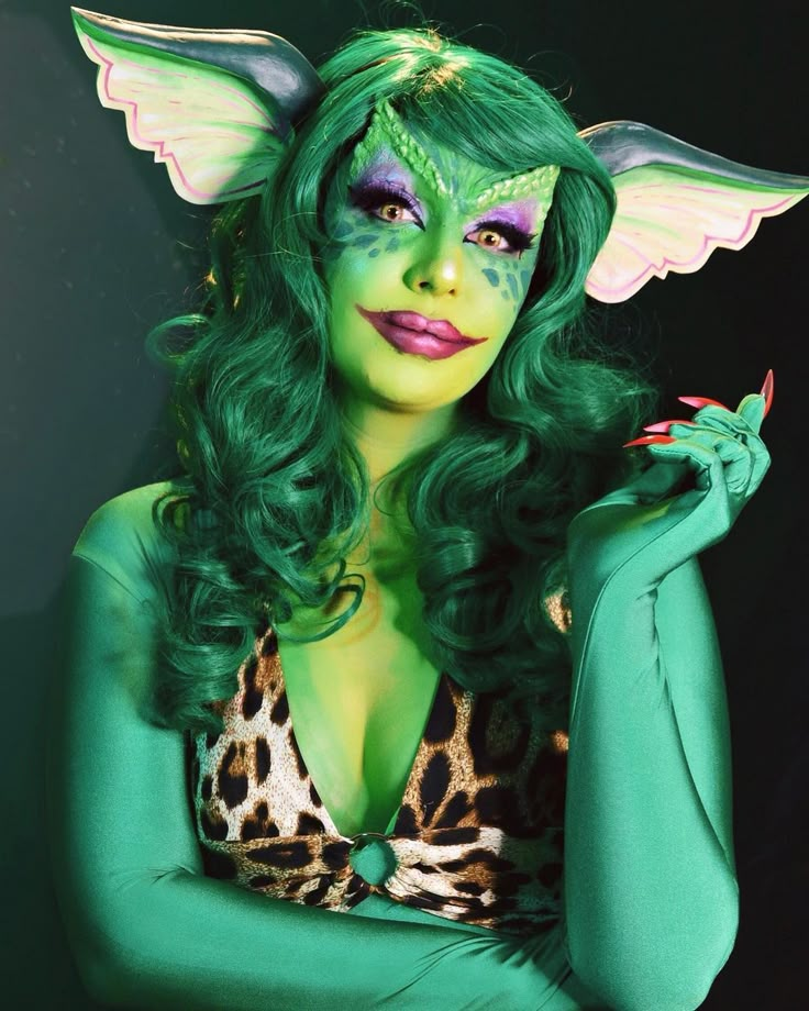 a woman with green hair and makeup is posing for the camera wearing a cat costume