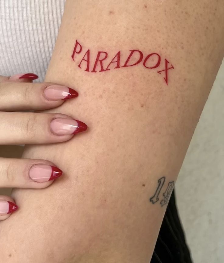 a woman's arm with the word paradox tattooed on her left side