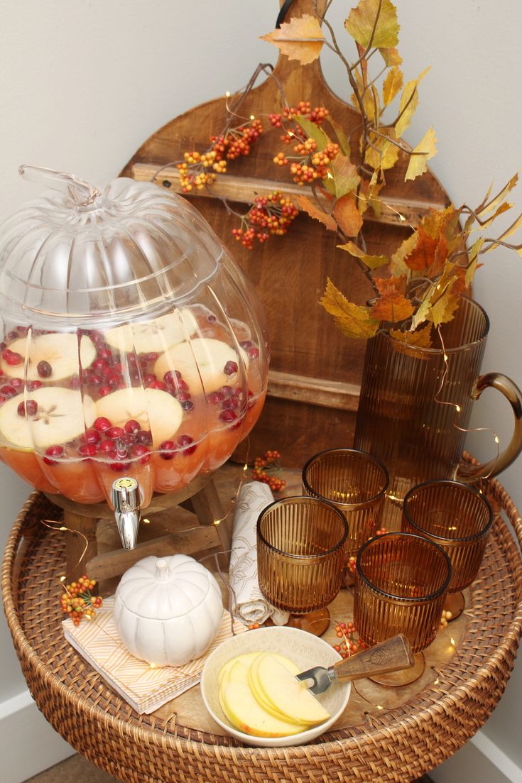 an assortment of fruit in a glass bowl on a wicker table next to other items