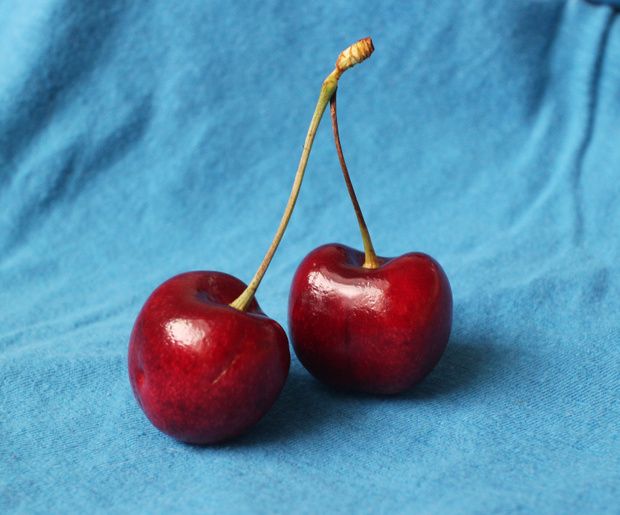 two cherries sitting on top of a blue cloth