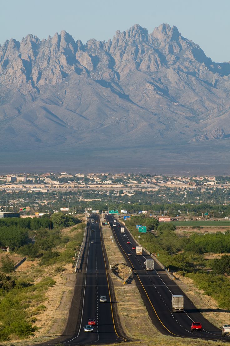 a highway with mountains in the background and cars driving down one lane on both sides