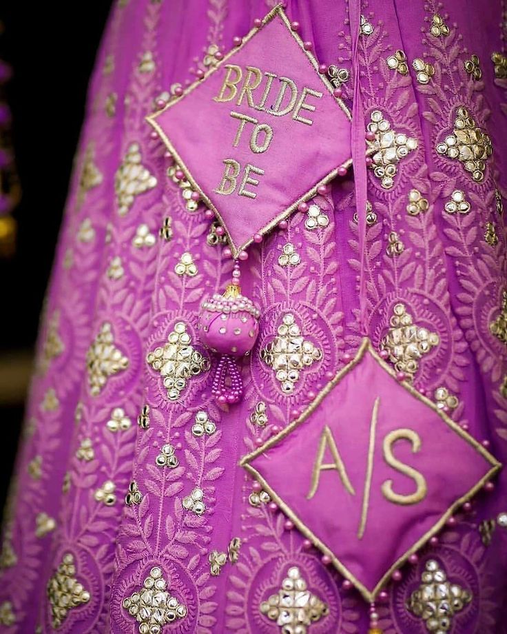 the bride to be badge is attached to a purple wedding dress with gold embellishments